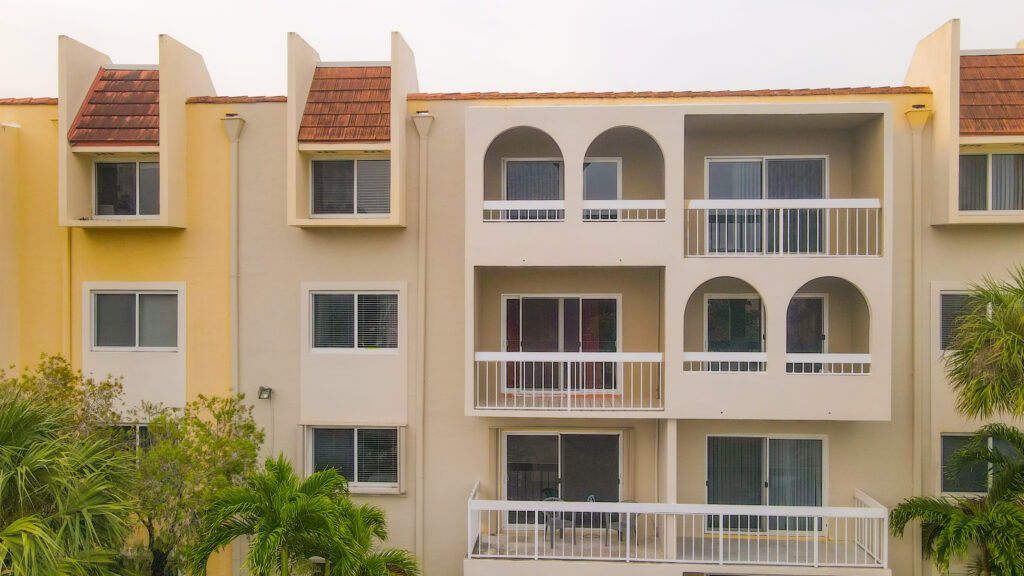 Condominium building exterior featuring balconies and large windows, showcasing Oratso Corporation's window and door solutions in South Florida.
