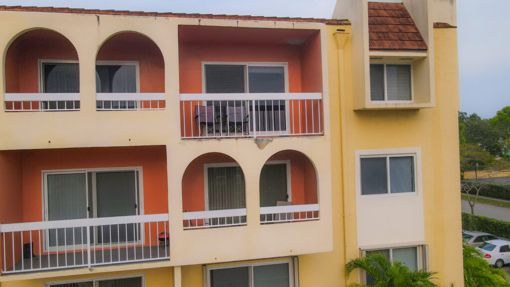 Condominium building exterior with balconies, featuring orange and yellow walls, emphasizing Oratso Corporation's focus on residential properties in South Florida.