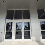 Modern glass double doors with large windows, showcasing the entrance to a commercial building, relevant to Oratso Corp's door solutions.