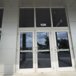 Glass entrance doors with number 128, showcasing Oratso Corporation's door solutions for residential and commercial needs.