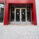 Double glass doors with red frame at Sunset Place Mall, showcasing Oratso Corporation's door installation.