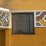 Colorful cultural art center window with decorative patterns on a yellow wall, showcasing Oratso Corp's design elements related to doors and windows.