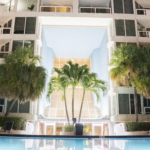 Grand apartment building entrance with palm trees and illuminated architecture, reflecting Oratso Corporation's luxury apartments in Miami.