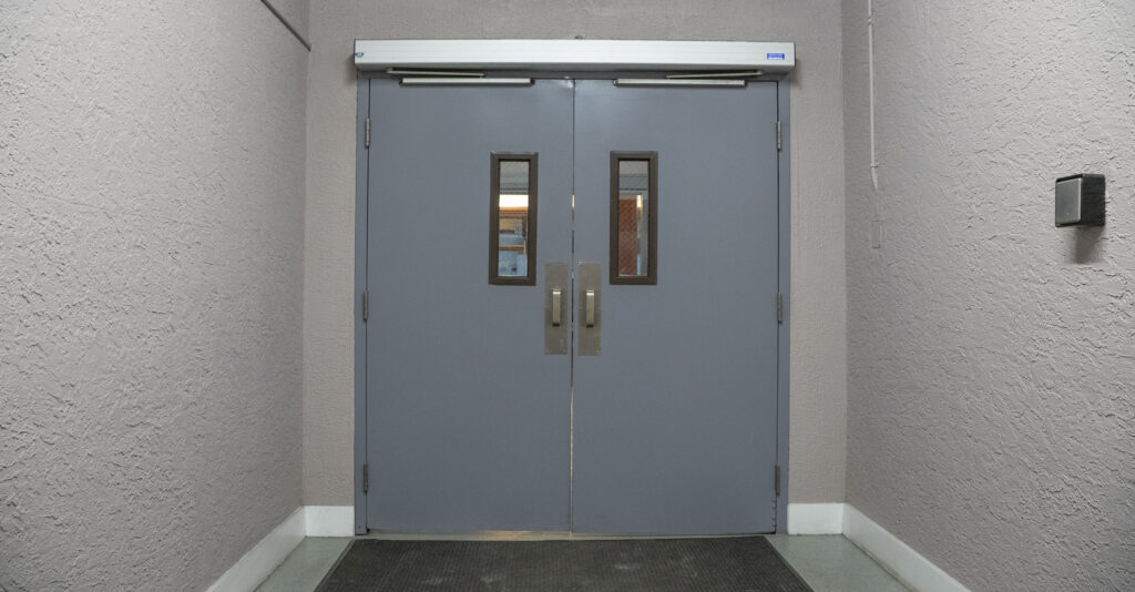 Automatic impact doors leading to a grand apartment entrance, showcasing modern design and accessibility features in a Miami setting.