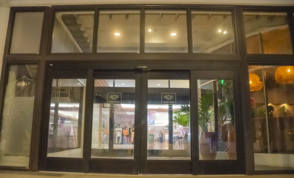 Automatic glass doors leading into a modern apartment lobby, showcasing stylish interior design and greenery, emphasizing Oratso Corporation's focus on quality apartments in Miami.