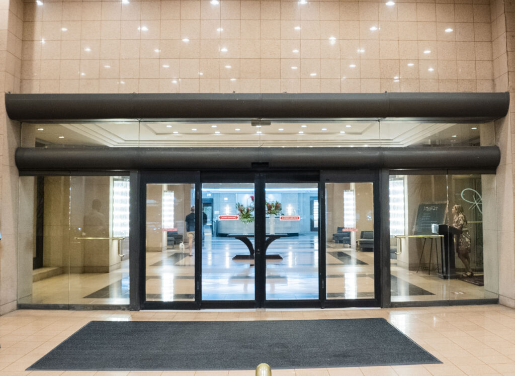 Automatic glass doors leading to a stylish apartment lobby with elegant decor and seating areas, showcasing Oratso Corporation's modern architectural design.